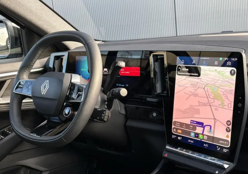 Vue intérieure côté conducteur du tableau de bord noir avec grand écran tactile vertical et volant Renault moderne.