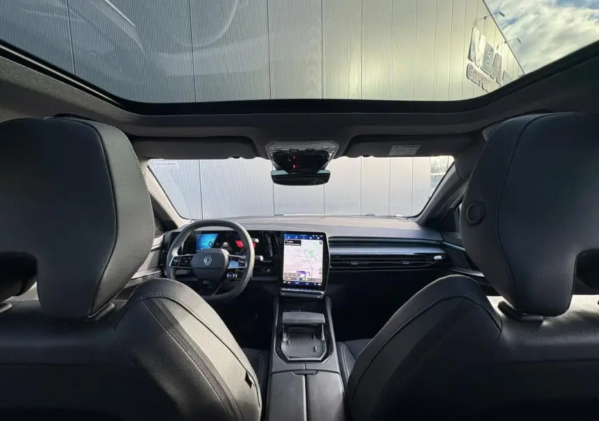 Intérieur Renault Austral E-Tech vu de l'arrière, toit panoramique, tableau de bord avec écran tactile vertical et volant noir.