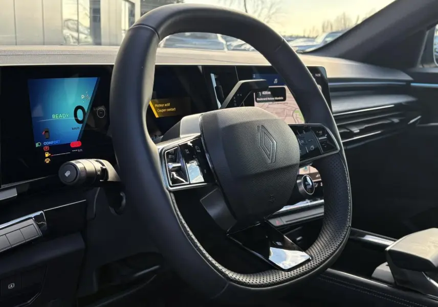 Vue intérieure du volant Renault Austral E-Tech avec tableau de bord numérique et écran central tactile, ambiance noire moderne.