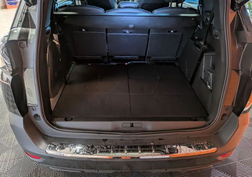 Coffre ouvert vu de l’arrière d’un Peugeot 5008 noir 2024, montrant l’espace de chargement et la banquette arrière.