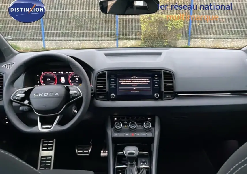 Vue intérieure frontale du tableau de bord et volant noir de la Skoda Karoq gris argent 2025 avec écran central et boîte auto.