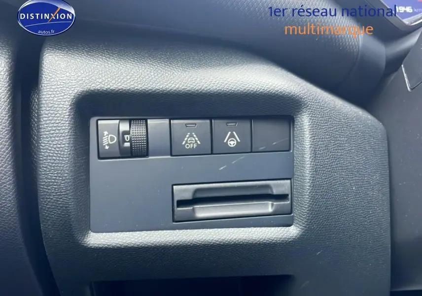 Gros plan sur les commandes de réglage des phares et d’aide à la conduite du tableau de bord noir d’une Citroën C5 Aircross.