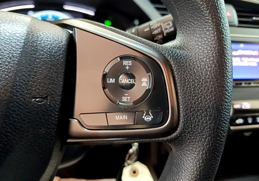 Gros plan sur les commandes du régulateur adaptatif au volant cuir noir de la Honda Civic gris foncé 2020.