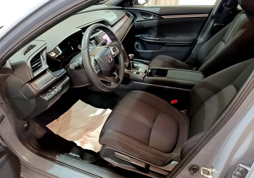 Vue intérieure côté conducteur de la Honda Civic 1.0 i-VTEC Exclusive 2020 avec sièges noirs et volant cuir.