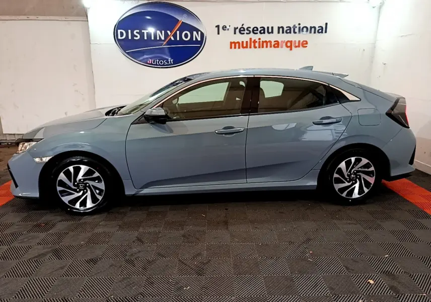 Vue de profil côté gauche d'une Honda Civic 1.0 i-VTEC Exclusive gris foncé avec jantes alliage au showroom.