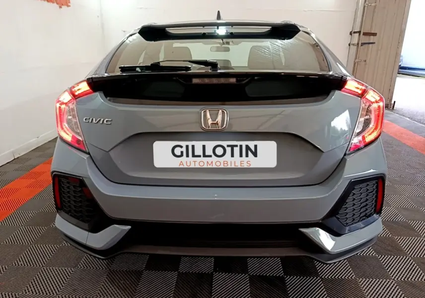 Vue arrière d'une Honda Civic gris foncé 2020 avec feux LED allumés et logo Honda visible sur le coffre.