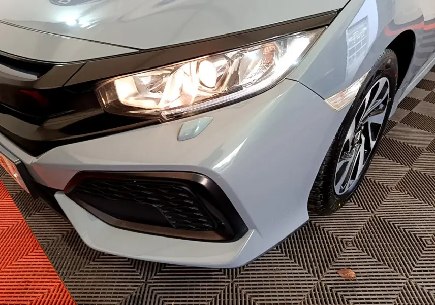 Gros plan sur l'avant droit gris clair d'une Honda Civic 2020 avec phare allumé et jante alliage noire.