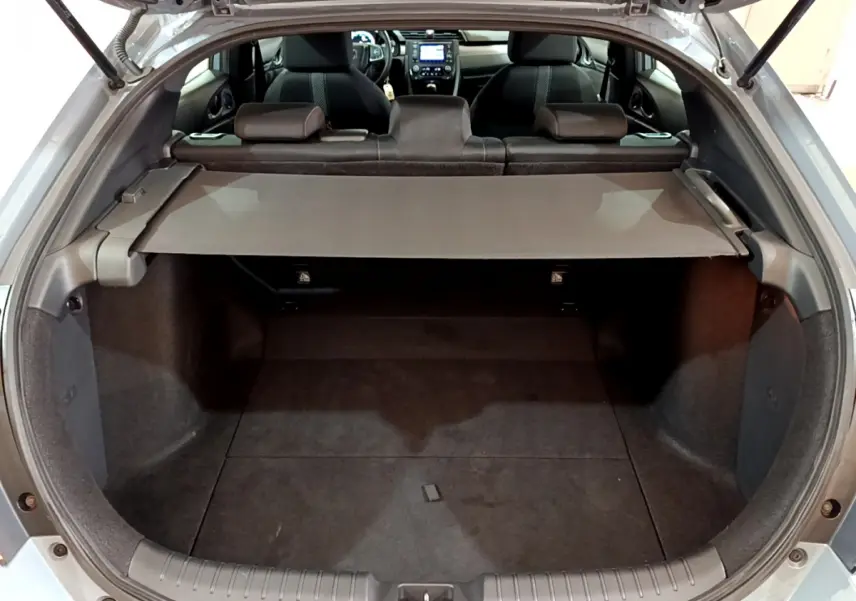 Vue arrière ouverte sur le coffre spacieux d'une Honda Civic 1.0 i-VTEC gris foncé avec banquette rabattue et tablette de couverture.