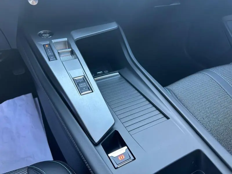 Vue rapprochée de la console centrale noire du Peugeot 308 SW 2024, avec levier de boîte auto et bouton Drive Mode.