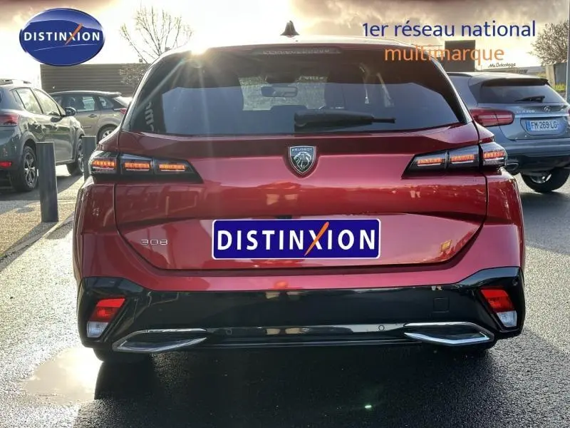 Vue arrière d'une Peugeot 308 SW 2024 en Rouge Elixir, avec feux arrière LED et logo distinctif au centre du hayon.