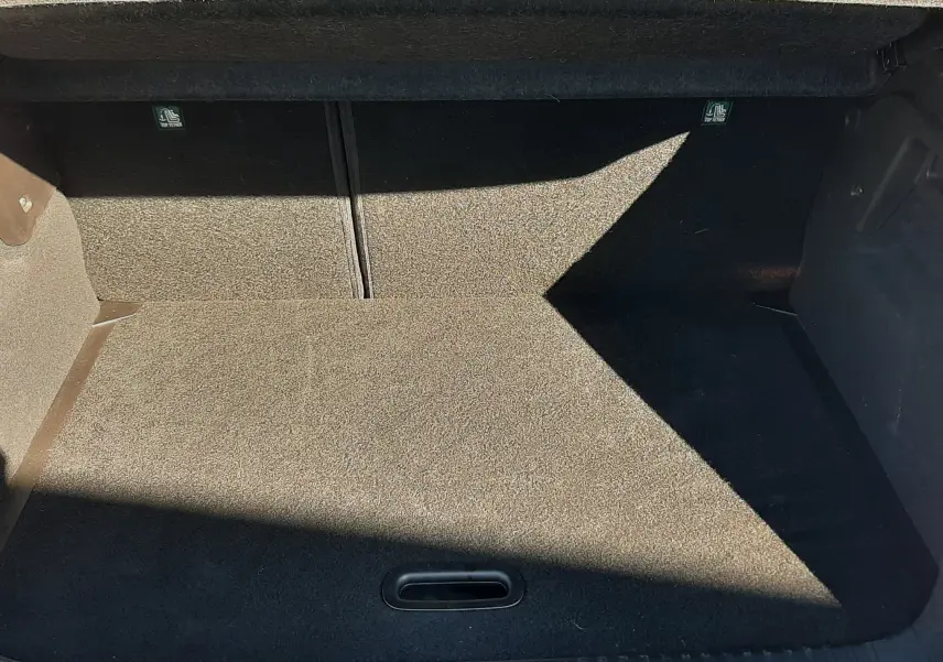 Coffre ouvert vu de l'arrière d'un Renault Captur E-Tech blanc nacré avec intérieur noir, montrant l'espace de chargement vide.