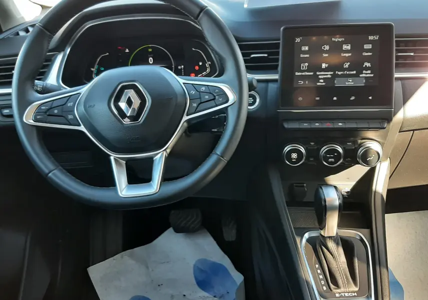 Vue intérieure centrée sur le volant et la console centrale du Renault Captur E-Tech 145ch Intens avec écran tactile et levier de vitesse.