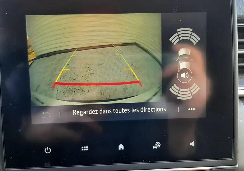 Écran central montrant la caméra de recul avec guidage coloré et alertes de proximité sur Renault Captur blanc nacré.