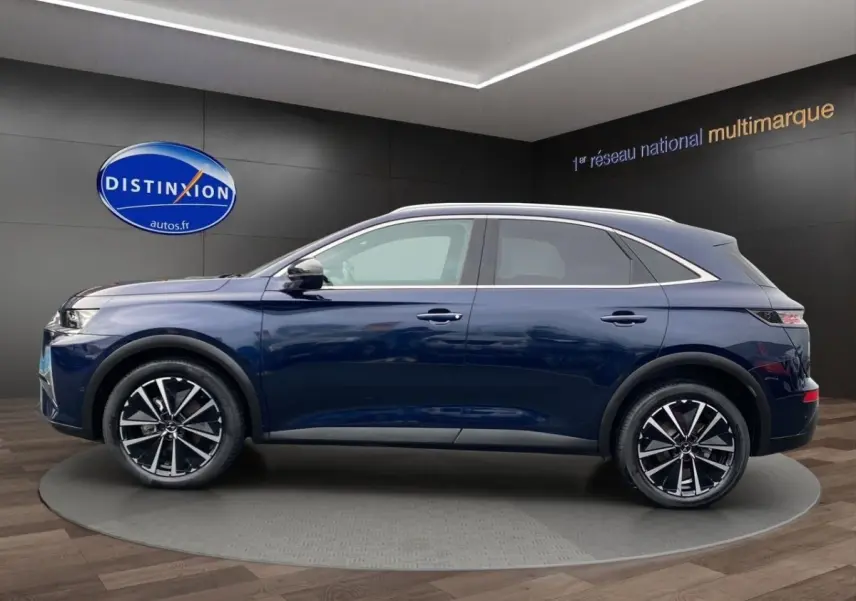 Vue latérale droite d'un DS7 Crossback bleu 2024 avec jantes alliage noires et toit argenté en showroom.