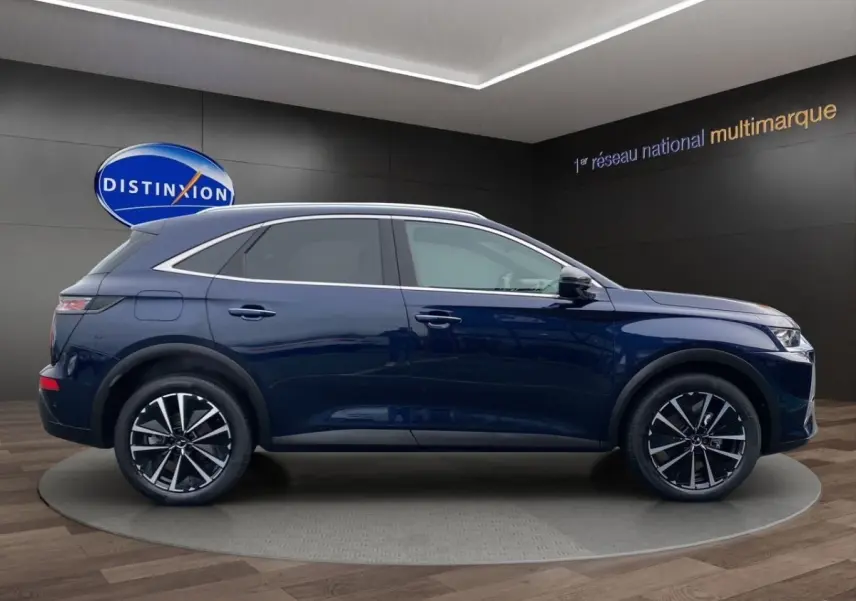 Vue latérale droite du DS7 Crossback bleu 2024 avec jantes alliage et toit chromé dans un showroom.