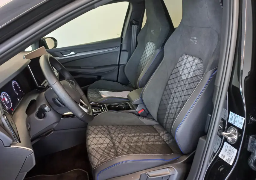 Vue intérieure côté conducteur de la Volkswagen Golf 1.5 eTSI R-Line 2025 avec sièges sport en tissu et alcantara noir.