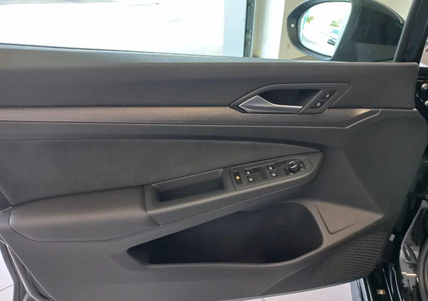 Vue intérieure de la porte côté gauche de la Volkswagen Golf 1.5 eTSI R-Line 2025 en noir ébène avec commandes électriques.