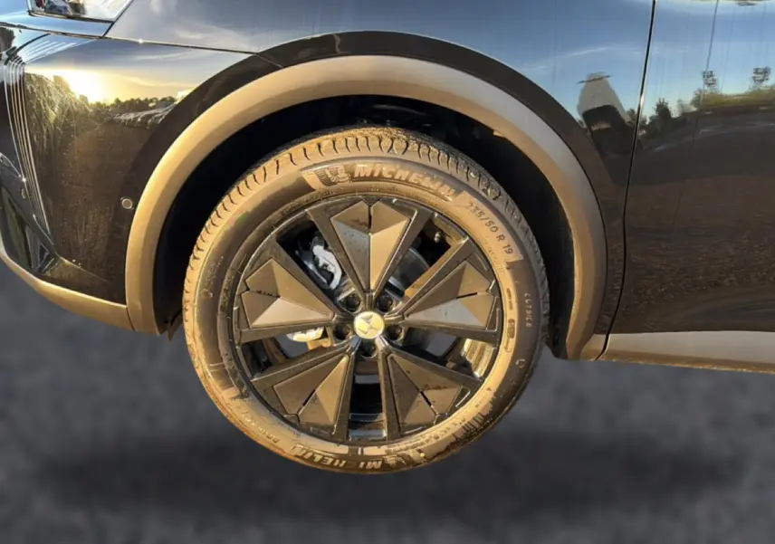 Gros plan sur la roue avant gauche noire du DS7 1.5 BlueHDi 130 Performance Line avec jante alu noire à motifs géométriques.