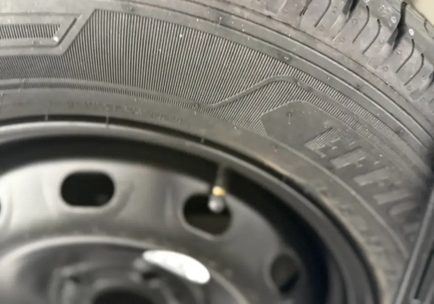 Gros plan sur la roue de secours noire du Renault Trafic Combi gris urbain, montrant le pneu et la jante acier.