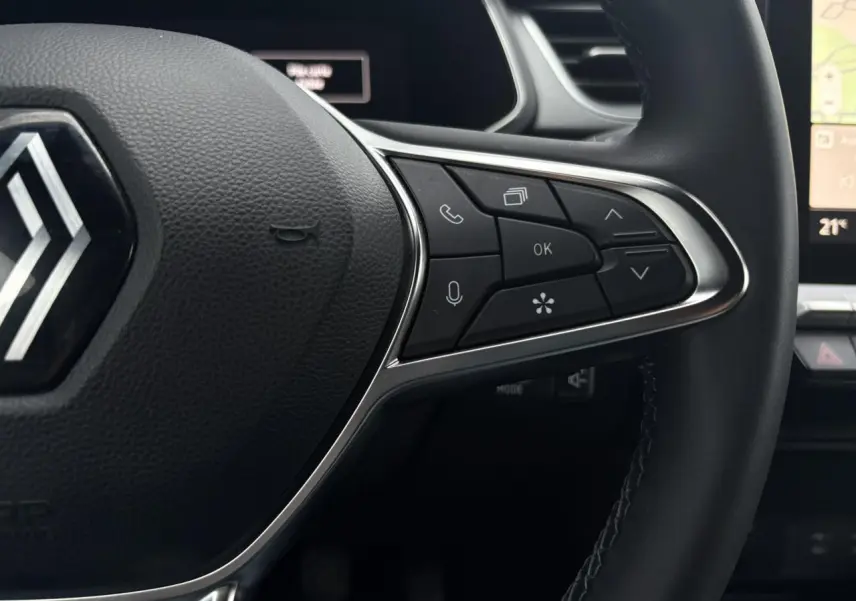 Gros plan sur la partie droite du volant noir du Renault Captur 2025 avec commandes multifonctions et tableau de bord numérique en arrière-plan.