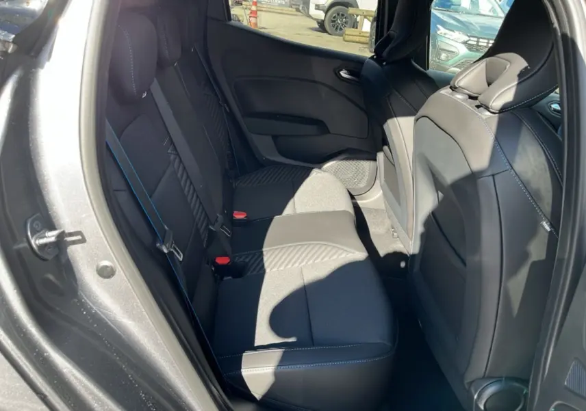 Vue intérieure côté gauche montrant la banquette arrière en tissu et cuir gris avec surpiqûres bleues d’une Renault Clio gris schiste.