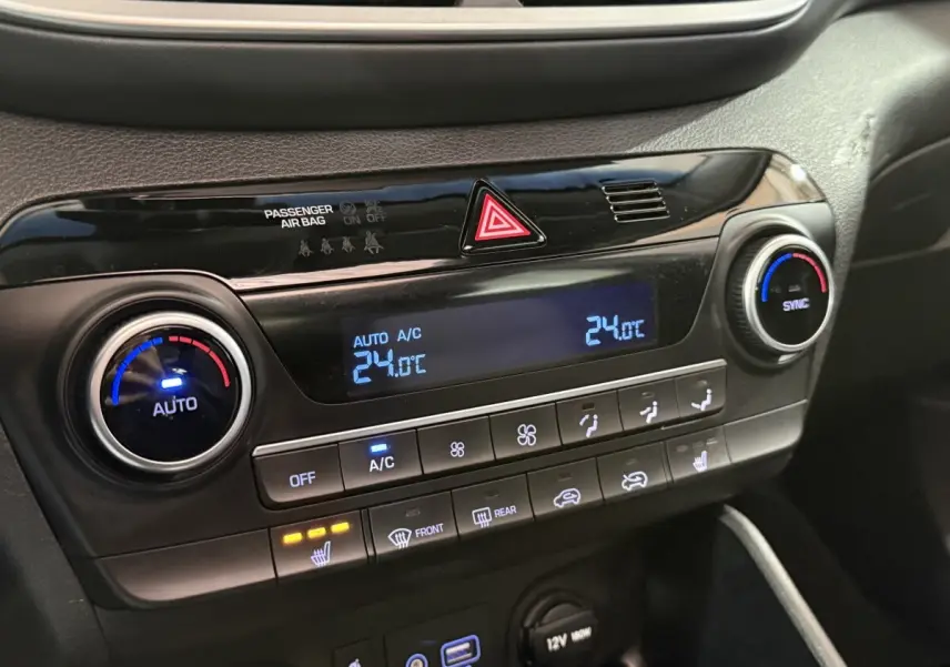 Vue rapprochée du tableau de bord noir du Hyundai Tucson 2019, affichage digital de la climatisation à 24°C et commandes tactiles.