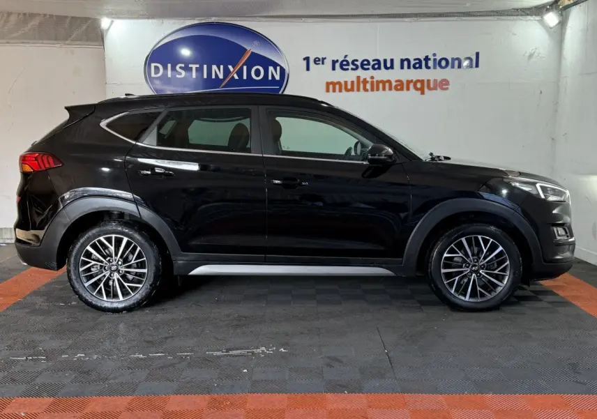 Vue latérale droite d’un Hyundai Tucson noir 2019 avec jantes alliage et rails de toit noirs dans un garage.