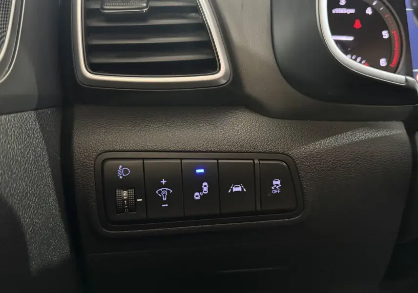 Gros plan sur les commandes de sécurité et d'éclairage du tableau de bord noir du Hyundai Tucson 2019.