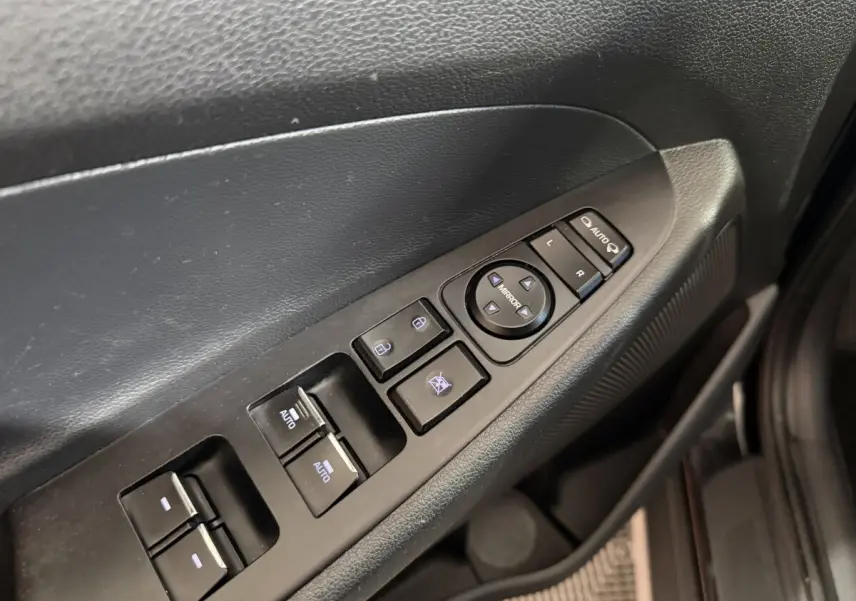 Gros plan sur les commandes de lève-vitres et rétroviseurs côté conducteur d’un Hyundai Tucson noir 2019.