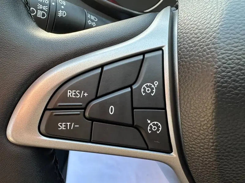 Gros plan sur les commandes de régulateur de vitesse au volant d'une Dacia Sandero 2025 blanc glacier.