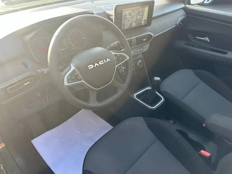 Vue intérieure côté conducteur du Dacia Sandero 2025, volant multifonction et écran tactile central visibles.