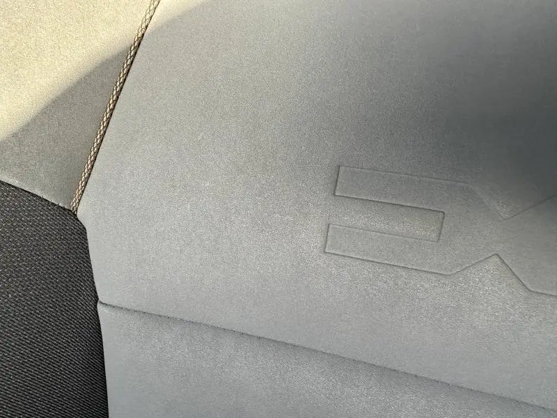 Détail du tissu gris clair avec surpiqûres et embossage "EXTREME" sur le siège avant d'une Dacia Sandero Stepway.