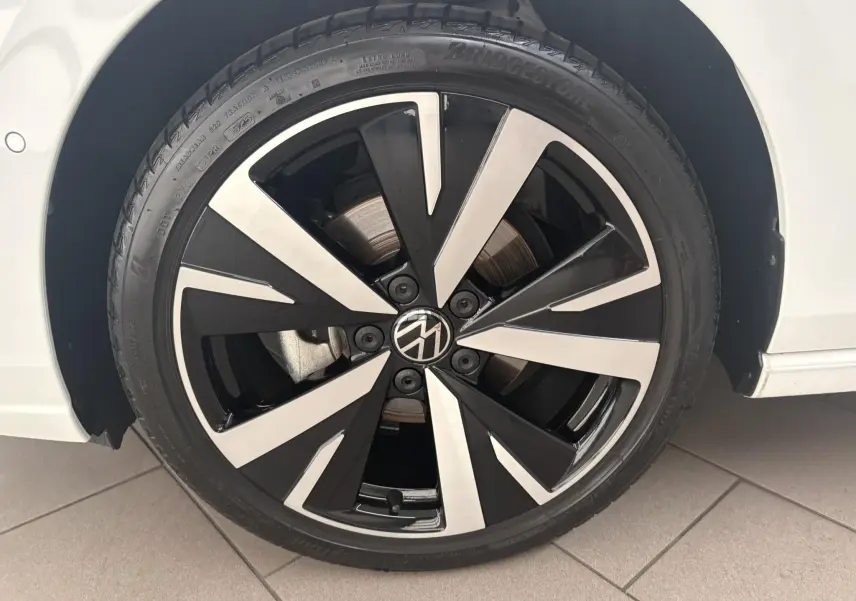 Gros plan sur la jante alliage 18'' Catania noire et argentée du côté gauche d'une Volkswagen Golf Blanc Oryx nacré.