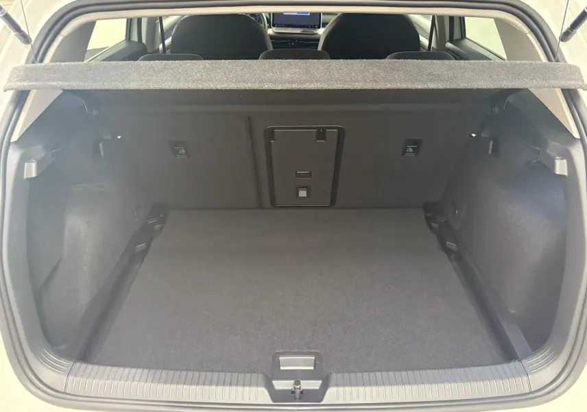 Vue du coffre ouvert d'une Volkswagen Golf 1.5 eTSI 116 BVM6 VW Edition blanc Oryx nacré, intérieur noir et tapis de sol.