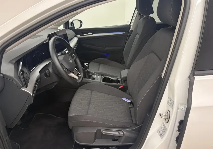 Intérieur avant droit de Volkswagen Golf 1.5 eTSI blanc Oryx nacré, sièges tissu gris et tableau de bord moderne.