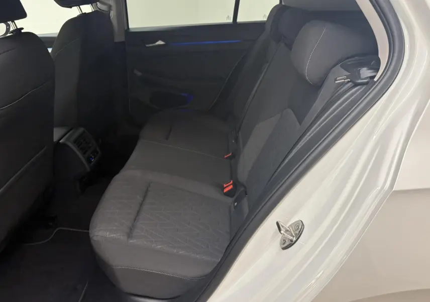 Vue intérieure côté arrière droit de la Volkswagen Golf 1.5 eTSI 2025 avec porte ouverte et sièges tissu gris.