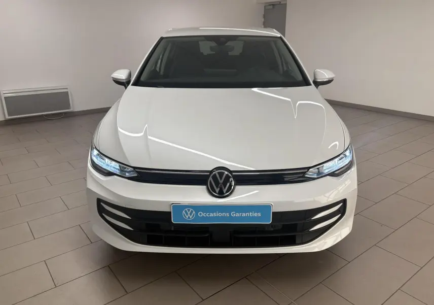 Vue frontale d'une Volkswagen Golf 1.5 eTSI 116 BVM6 VW Edition blanche nacrée avec phares LED allumés en intérieur.