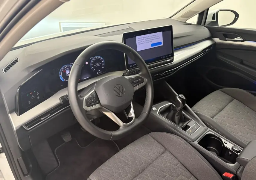 Vue intérieure côté conducteur de la Volkswagen Golf 1.5 eTSI 2025 avec tableau de bord numérique et boîte manuelle.