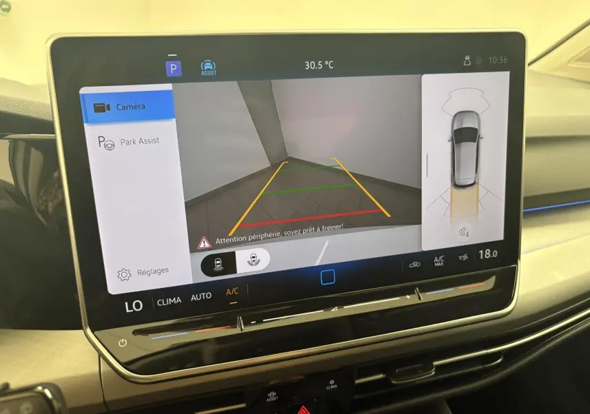 Écran tactile intérieur affichant la caméra de recul et l'assistance au stationnement d'une Volkswagen Golf Blanc Oryx nacré.