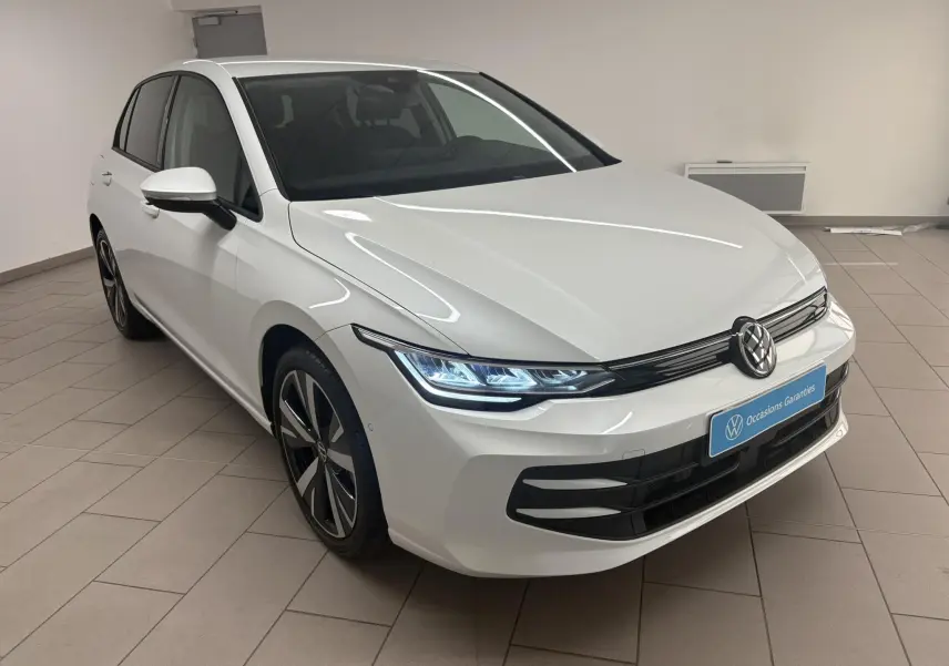 Volkswagen Golf 1.5 eTSI 2025 vue 3/4 avant en Blanc Oryx nacré avec jantes alliage 18'' Catania et phares LED allumés.