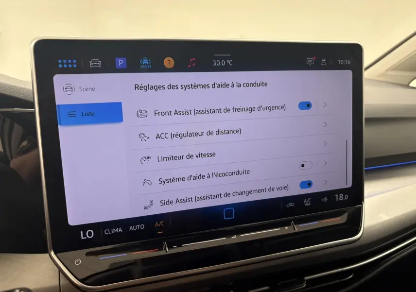 Écran tactile central affichant les réglages d'aide à la conduite dans une Volkswagen Golf 1.5 eTSI blanc Oryx nacré.