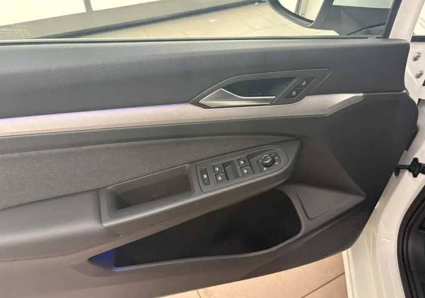 Intérieur côté gauche de la porte avant d'une Volkswagen Golf 2025 blanc Oryx nacré, avec commandes de vitres et serrure.