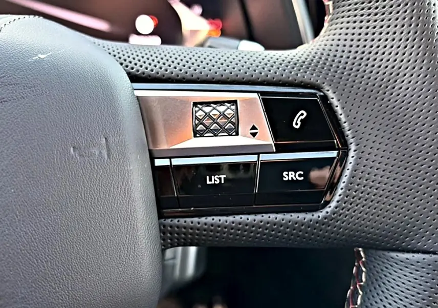 Gros plan sur les commandes noires et argentées du volant cuir perforé du DS7 1.5 BlueHDi 130 Performance Line.