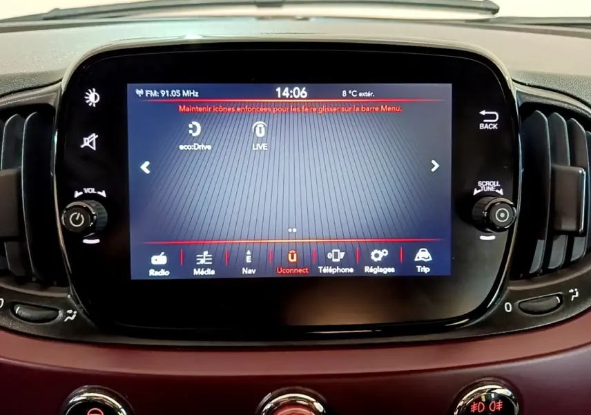 Écran tactile central du tableau de bord d’une FIAT 500 rouge, affichant le menu Uconnect et commandes autour.