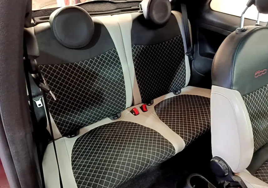 Vue intérieure sur la banquette arrière et siège avant de la FIAT 500 1.0 rouge avec sellerie noire et beige à motifs losanges.