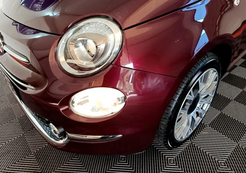 Gros plan sur l'avant droit de la FIAT 500 rouge, mettant en valeur le phare rond et la jante alu design.