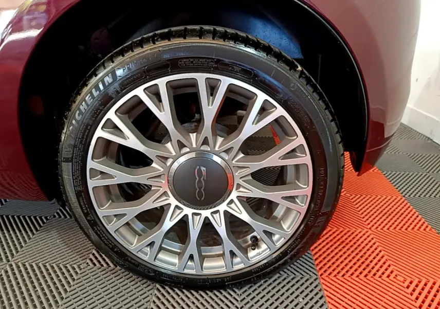 Gros plan sur la roue avant droite rouge de la FIAT 500 1.0 70ch BSG Star avec jante alliage argentée à multiples branches.