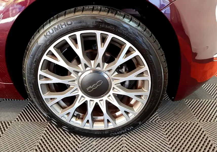 Gros plan sur la roue avant gauche d'une FIAT 500 rouge 2021, mettant en valeur la jante alliage multibranches.