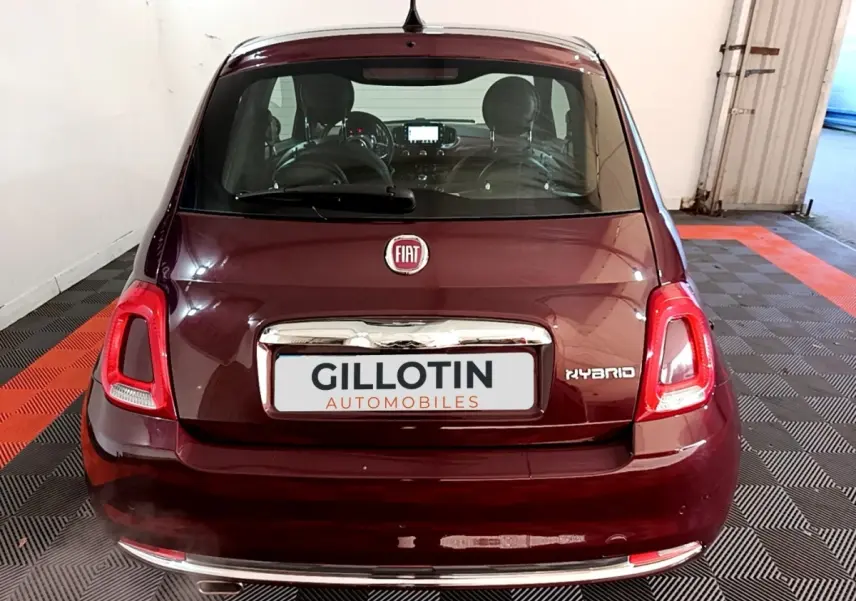 Vue arrière d'une Fiat 500 rouge hybride, avec logo FIAT et badge Hybrid visibles sur le coffre.