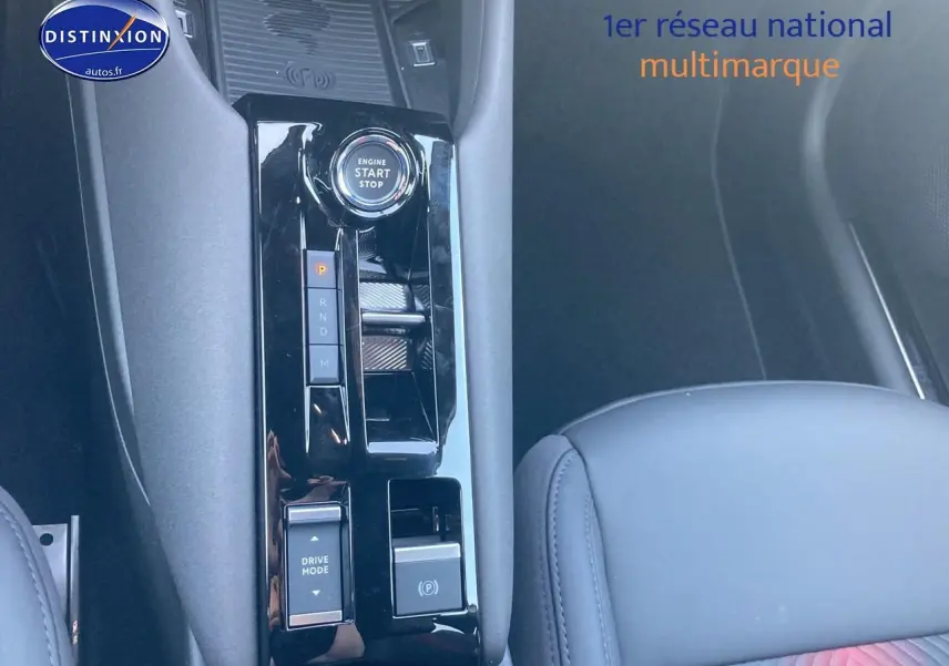 Gros plan sur la console centrale noire brillante de l'Alfa Romeo Junior 1.2 hybride, avec bouton start/stop et levier de vitesses.